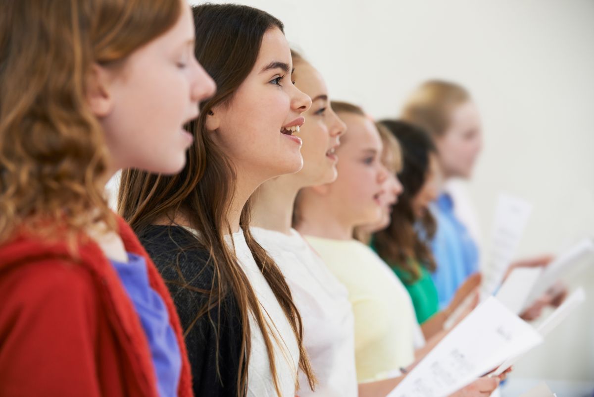 Student singing into a microphone in a recording studio